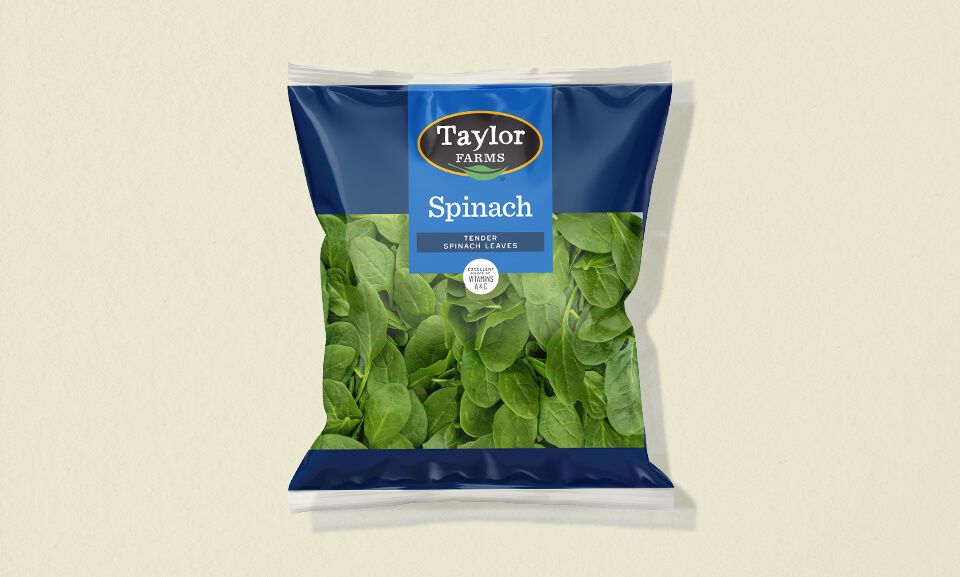 Fresh 9 oz spinach salad blend packaging from Taylor Farms with vibrant green leaves and a clear view of the product.