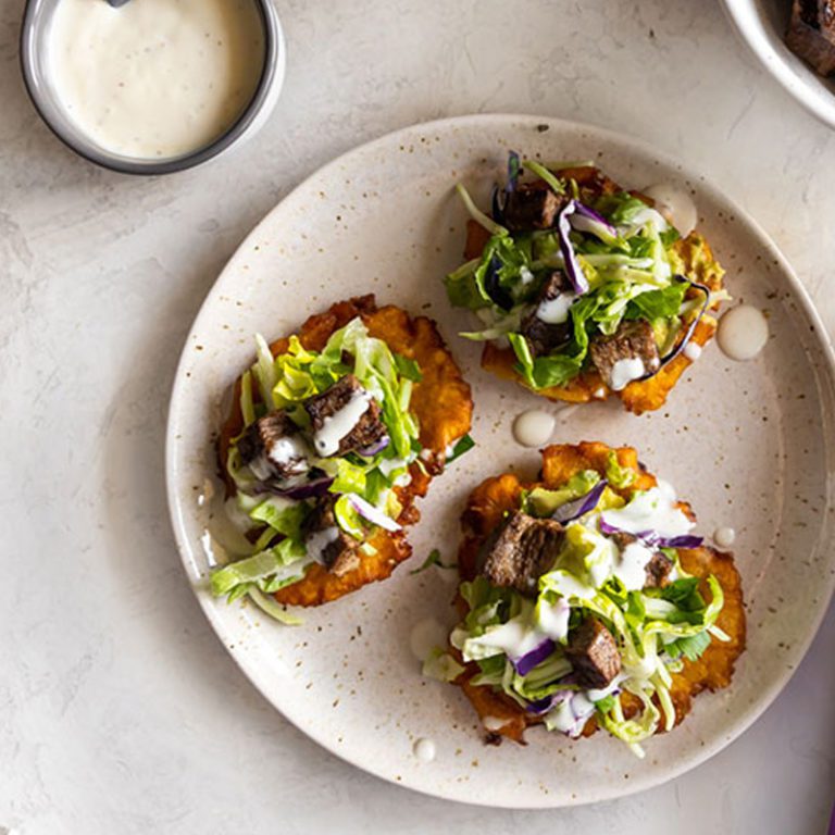 Carne asada tostones served with roasted garlic chopped salad for a delicious and colorful meal.