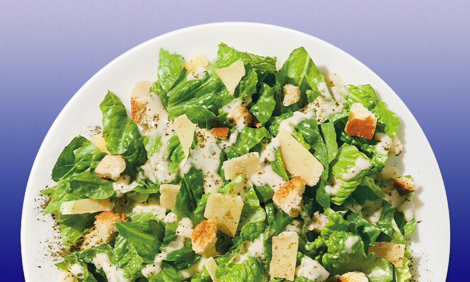 Ultimate Caesar salad kit with fresh romaine, creamy dressing, and crunchy croutons displayed attractively.