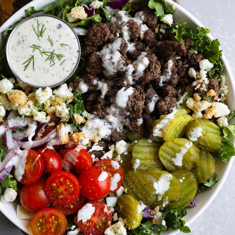 Colorful burger bowl featuring fresh greens, grilled beef, tomatoes, and cheese for a healthy meal option.