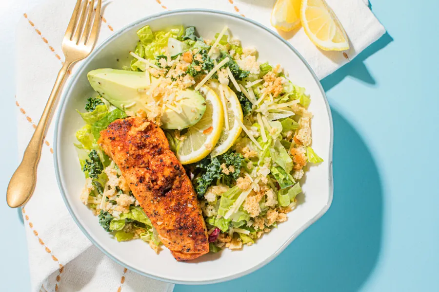 Taylor Farms Lemon Parmesan Salmon Salad on a plate with a blue background