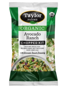 The Taylor Farms Organic Avocado Ranch Chopped Salad Kit package, showing cauliflower, broccoli stalk, red & green cabbage, chicory, carrots, kale, white tortilla chips, and the Avocado Ranch Dressing.