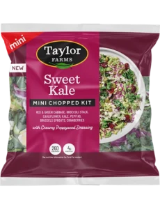 The Taylor Farms Sweet Kale Mini Chopped Salad Kit package, showing red & green cabbage, broccoli stalk, cauliflower, kale, pepitas, Brussels sprouts, cranberries, and poppyseed dressing.