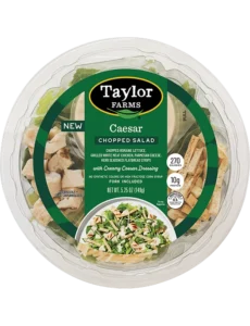 The Taylor Farms Caesar Chopped Salad Bowl package, showing romaine lettuce, grilled white meat chicken, parmesan cheese, herb-seasoned flatbread strips, and creamy Caesar dressing.