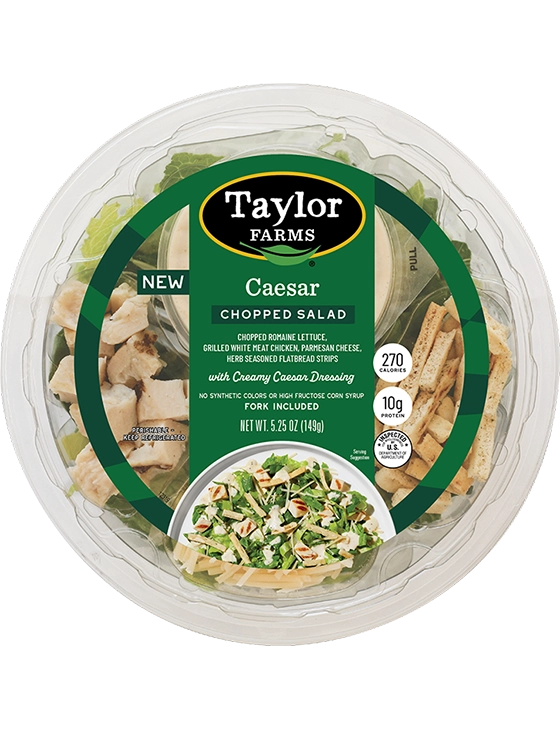 The Taylor Farms Caesar Chopped Salad Bowl package, showing romaine lettuce, grilled white meat chicken, parmesan cheese, herb-seasoned flatbread strips, and creamy Caesar dressing.