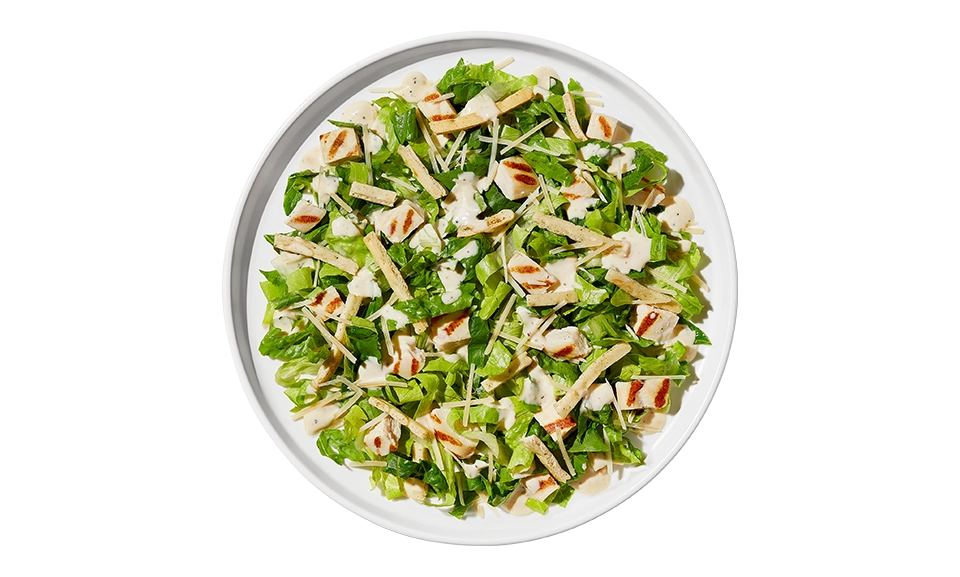 The Taylor Farms Caesar Chopped Salad Bowl package, showing romaine lettuce, grilled white meat chicken, parmesan cheese, herb-seasoned flatbread strips, and creamy Caesar dressing.