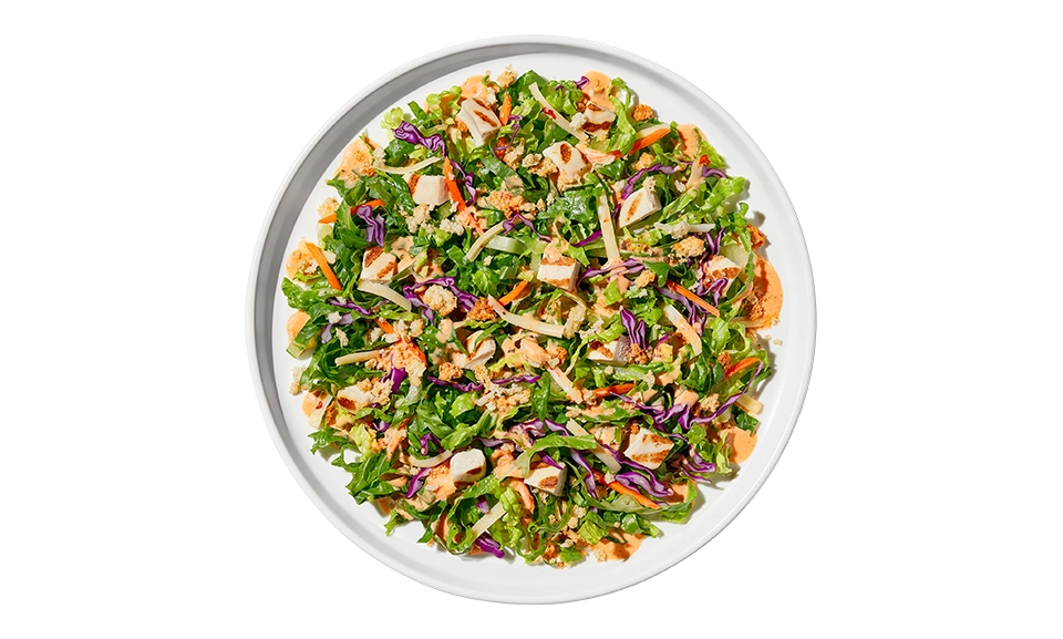 The Taylor Farms Nashville Hot Chopped Salad Bowl package, showing chopped romaine lettuce, red cabbage, carrots, grilled white meat chicken, pepper jack cheese, crouton crumbles, and Nashville hot ranch dressing.