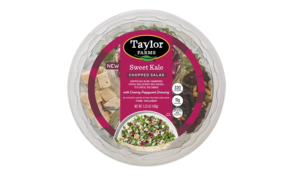 The Taylor Farms Sweet Kale Chopped Salad Bowl package, showing chopped kale and red cabbage, dried cranberries, pepitas, feta cheese, grilled white meat chicken, and creamy poppyseed dressing.