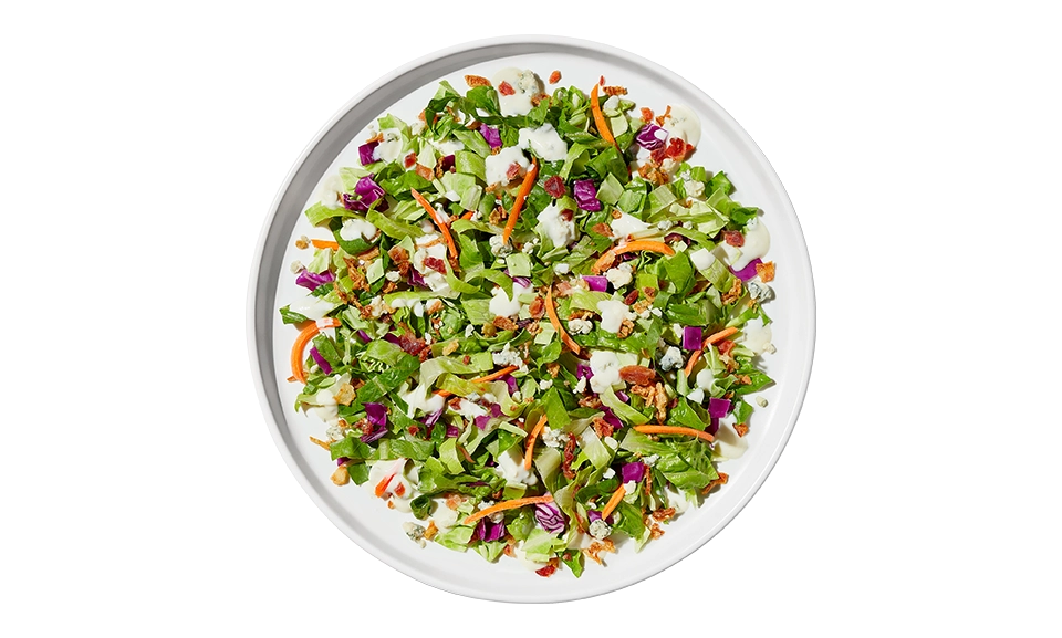 The Taylor Farms Wedge Chopped Salad Bowl package, showing romaine lettuce, red and green cabbage, carrots, bacon pieces, blue cheese crumbles, crispy onions, and creamy blue cheese dressing.