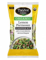 Taylor Farms Organic Lemon Parmesan Chopped Salad package, next to an open tortilla on a plate with the Lemon Parmesan Salad, topped with sliced avocado and a creamy sauce.